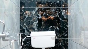A bathroom with a white toilet, marble walls, and a marble floor. - Hotel Mahalok Palace (Ujjain)