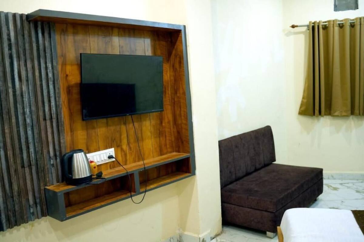 Ein Zimmer mit einem HolztV-Schrank, einem Flachbildfernseher, einer Couch und einem Vorhang.