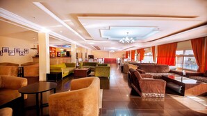 A hotel lobby with multiple seating areas, a reception desk, and a view of the outdoors. - Universal Hotel Enugu (Enugu)