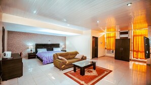 A modern hotel room with a large bed, a sofa, a coffee table, and a desk. - Universal Hotel Enugu (Enugu)