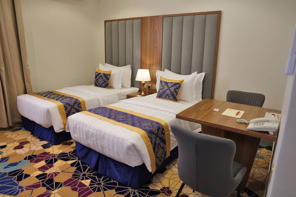 Ein Hotelzimmer mit zwei Betten, einem Schreibtisch und einem Stuhl.