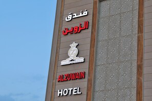 Hotellin kyltti, jossa on nimi »Alzuwain Hotel» ja arabiankielistä tekstiä.