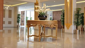 A luxurious lobby with a reflective floor, ornate golden furniture, and a large vase of white flowers. - alzuwain hotil (Arar)