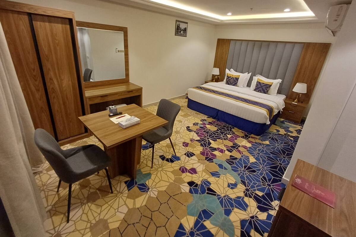 Ein Hotelzimmer mit Bett, Schreibtisch, Stuhl, Spiegel und einem gemusterten Boden.