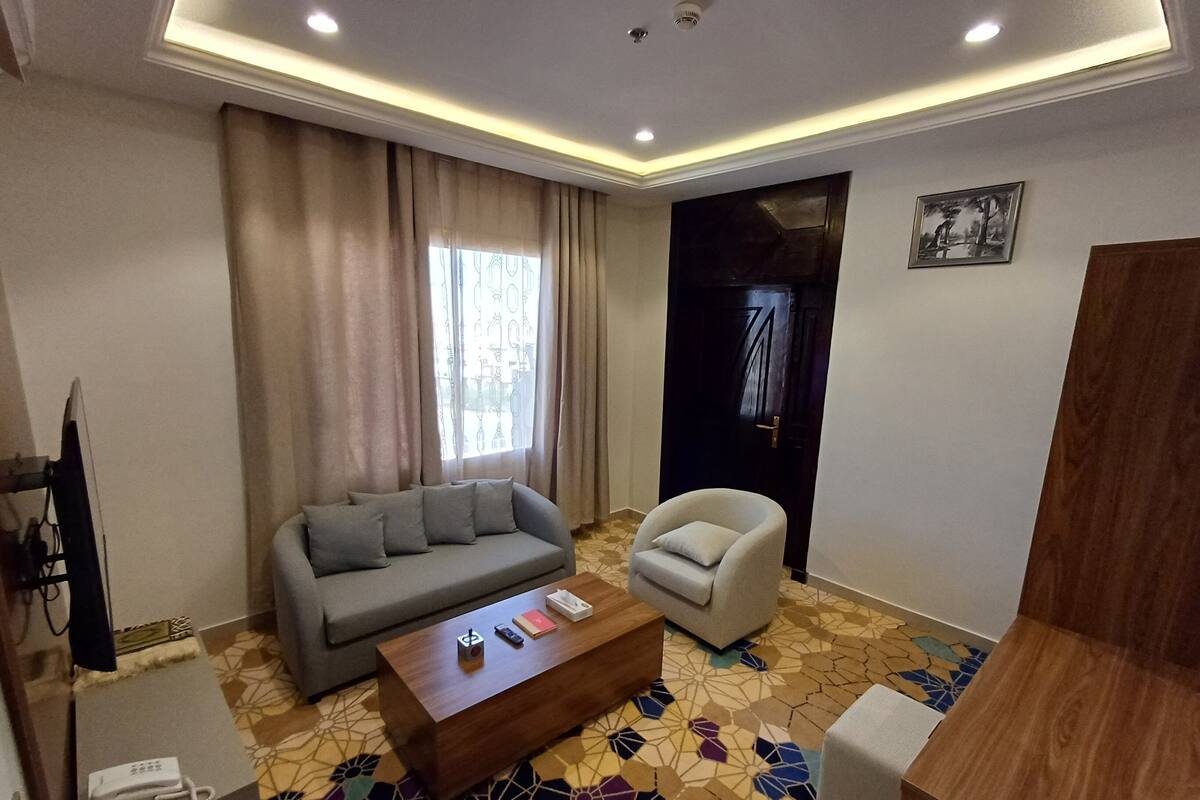 Ein modernes Wohnzimmer mit einem grauen Sofa, einem weißen Sessel, einem Holztisch und einem gestreiften Boden.