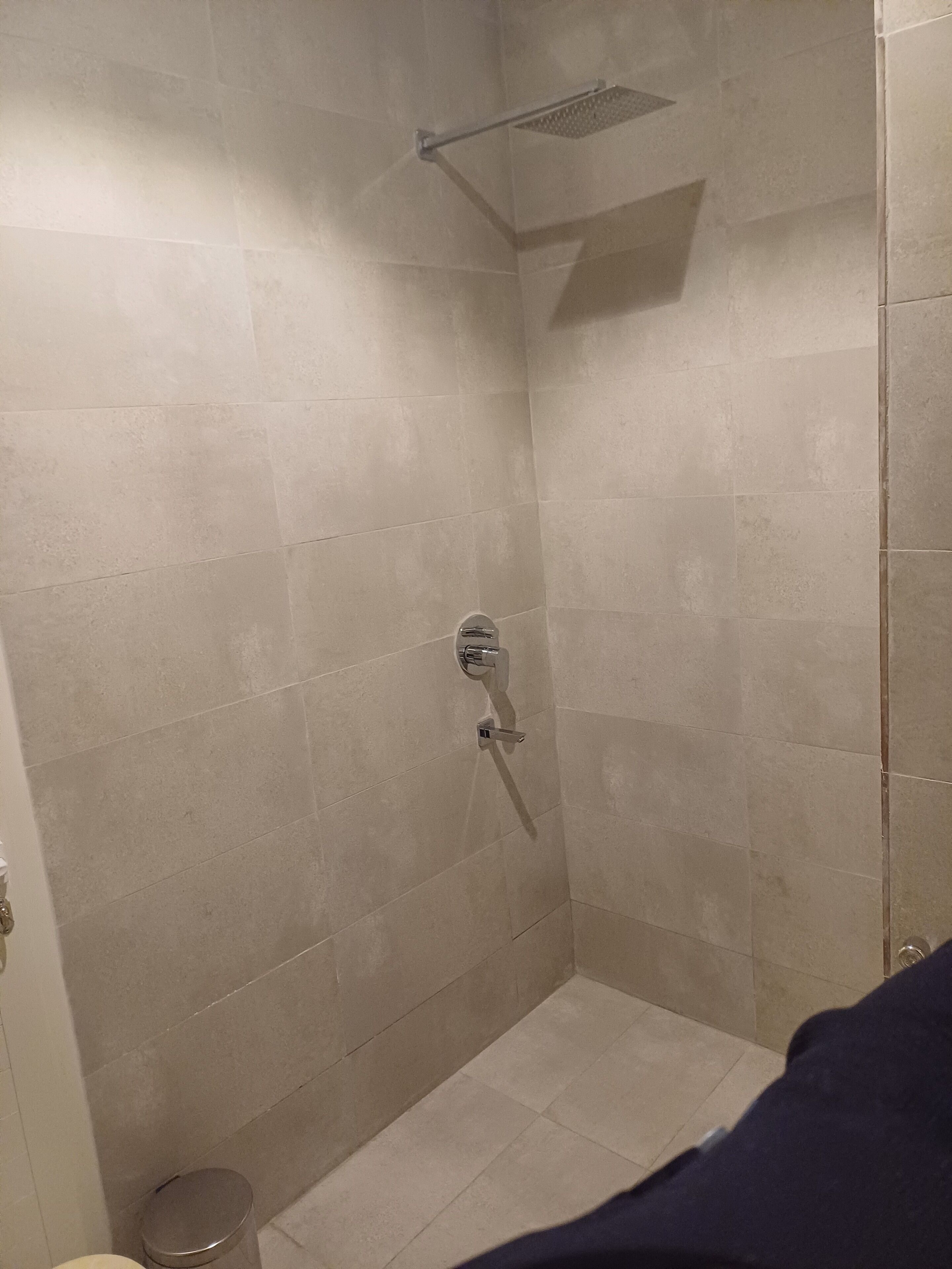 A small, tiled shower room with a showerhead and a handheld shower attachment.
