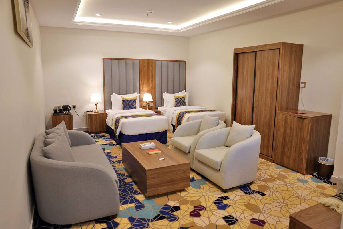 Ein Hotelzimmer mit zwei Betten, einem Schlafsofa, einem Couchtisch und einem Kleiderschrank.