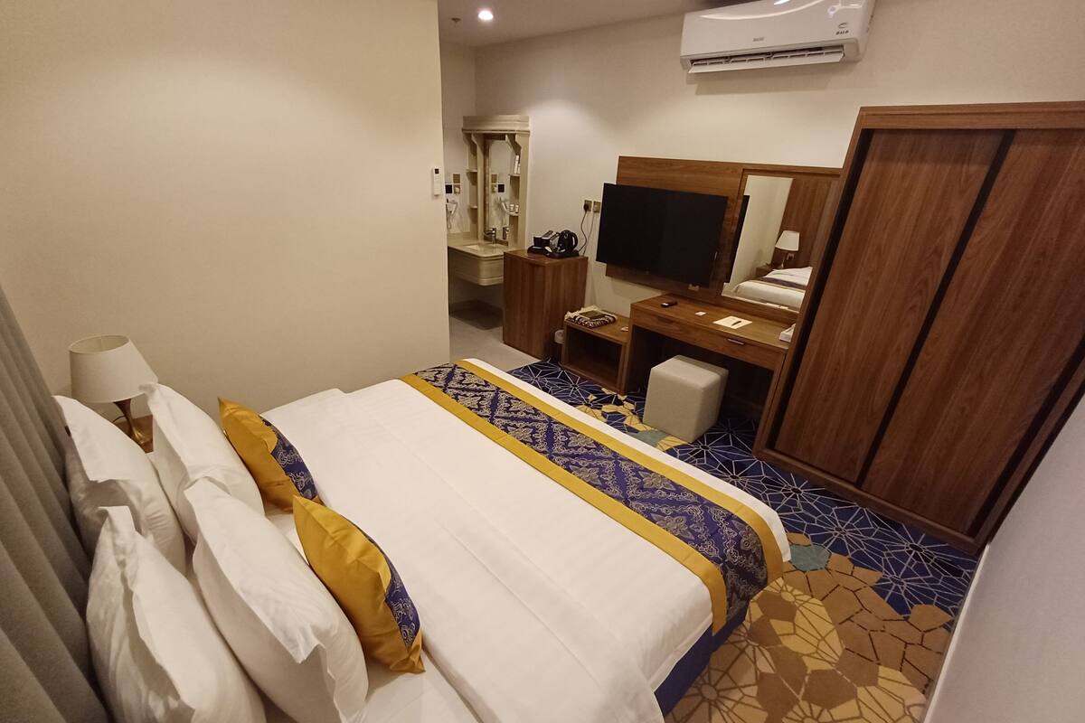 Ein Hotelzimmer mit Bett, Schreibtisch, Fernseher und Kleiderschrank.
