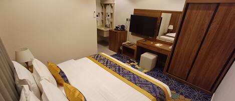 A hotel room with a bed, a desk, a television, and a wardrobe.
