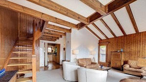 Ein großzügiger Wohnbereich mit einer Holztreppe, einem Esstisch und zwei Sofas.