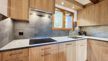 Une cuisine moderne avec des meubles en bois, une cuisinière encastrée et une fenêtre au-dessus de l’évier.