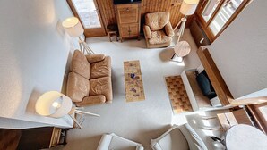 Ein modernes Wohnzimmer mit einer Couch, Sesseln, einem Couchtisch und einer Holzkabine.