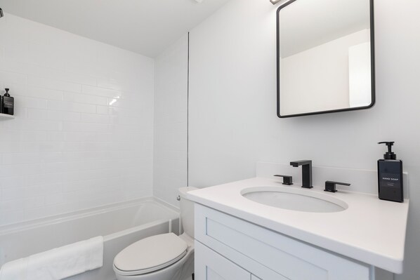 A modern bathroom with a white sink, black soap dispenser, and a mirror. - The Gallery Unit 101 (Alexandria)
