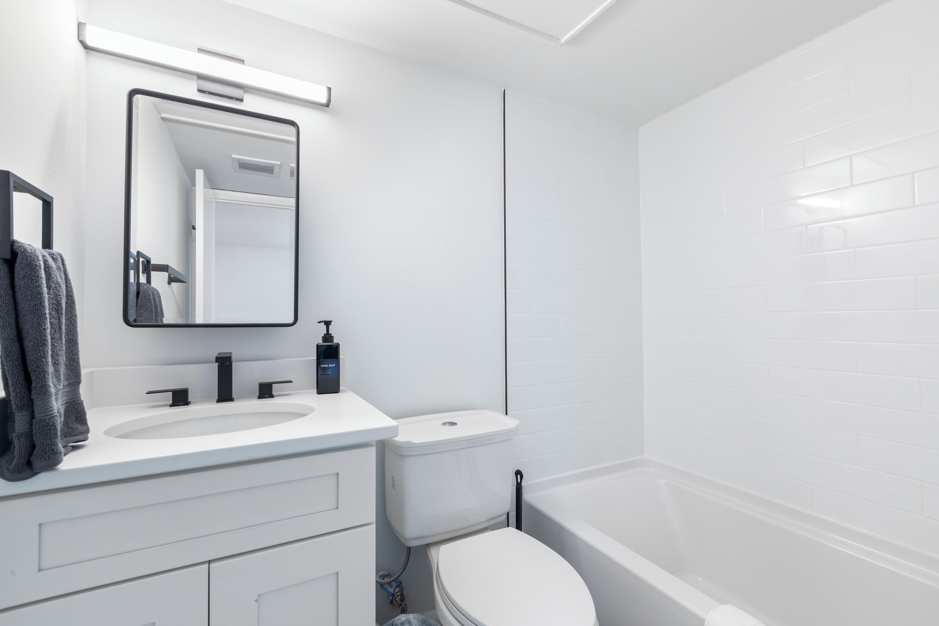A modern bathroom with a white sink, mirror, and toilet.