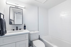A modern bathroom with a white sink, mirror, and toilet.
