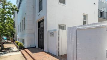 A white building with a brick pathway leading to the entrance.