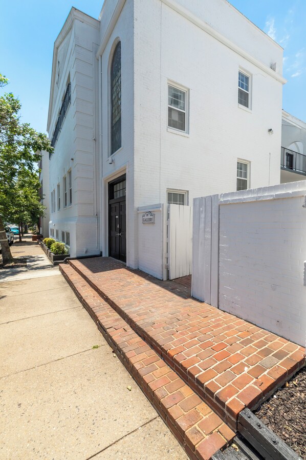 A white building with a brick pathway leading to the entrance.