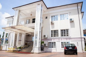 A two-story building with a covered entrance, a staircase, and a car parked in front. - Garden Atlantis Hotel (Enugu)