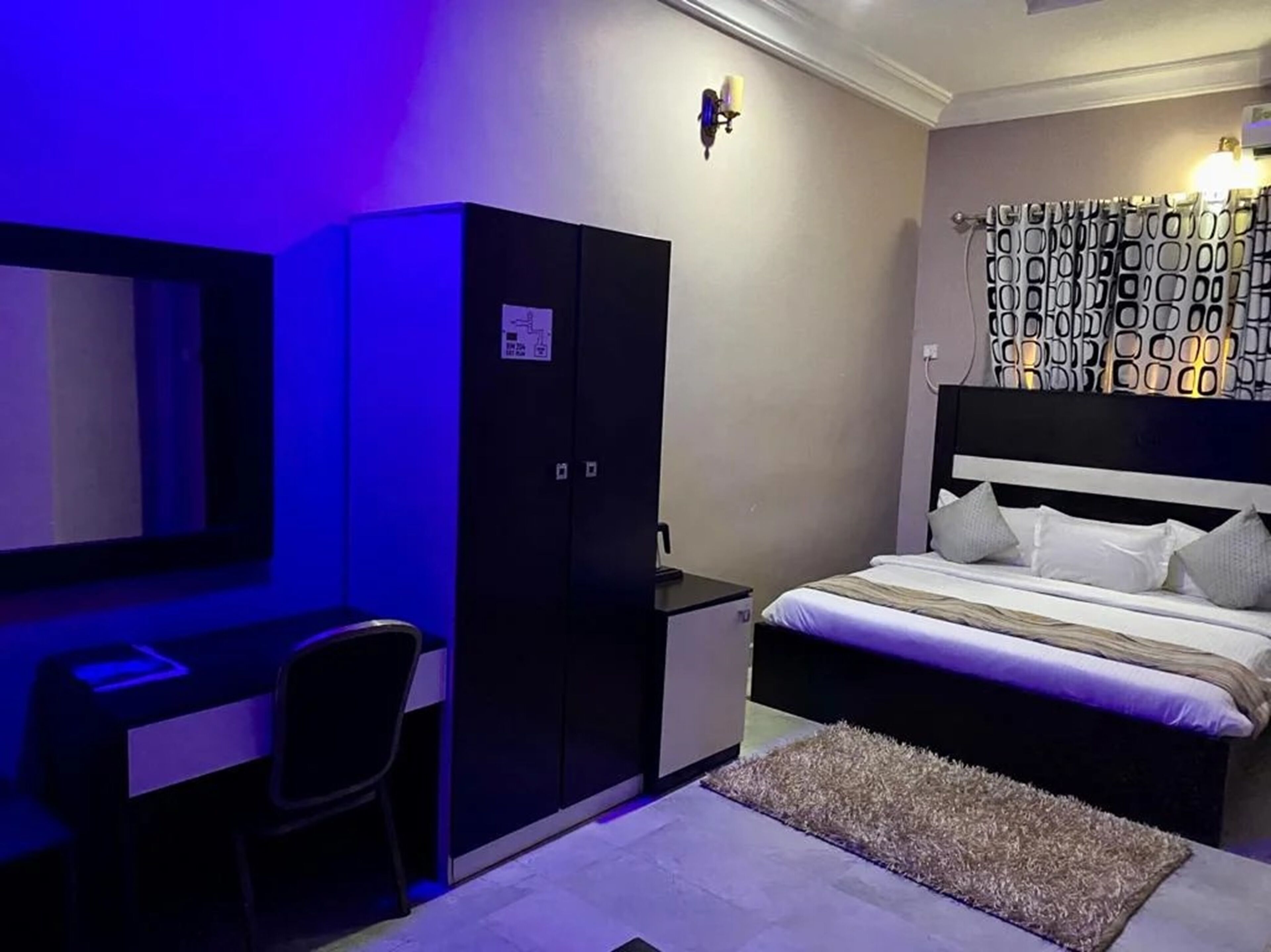 Un dormitorio con cama, escritorio, armario e iluminación instalada en la pared.