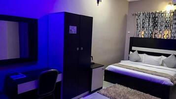 Un dormitorio con cama, escritorio, armario e iluminación instalada en la pared.