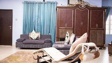A living room with a sofa, a chaise lounge, a large wardrobe, and a curtain.