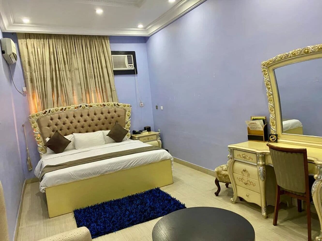 A bedroom with a bed, a dresser, a mirror, and a blue rug.
