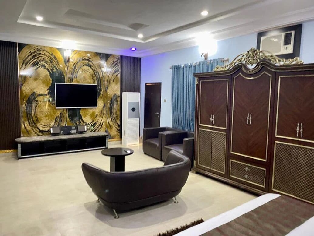 Un salón moderno con una televisión de pantalla plana, un sofá, un mueble y un detalle decorativo en la pared.