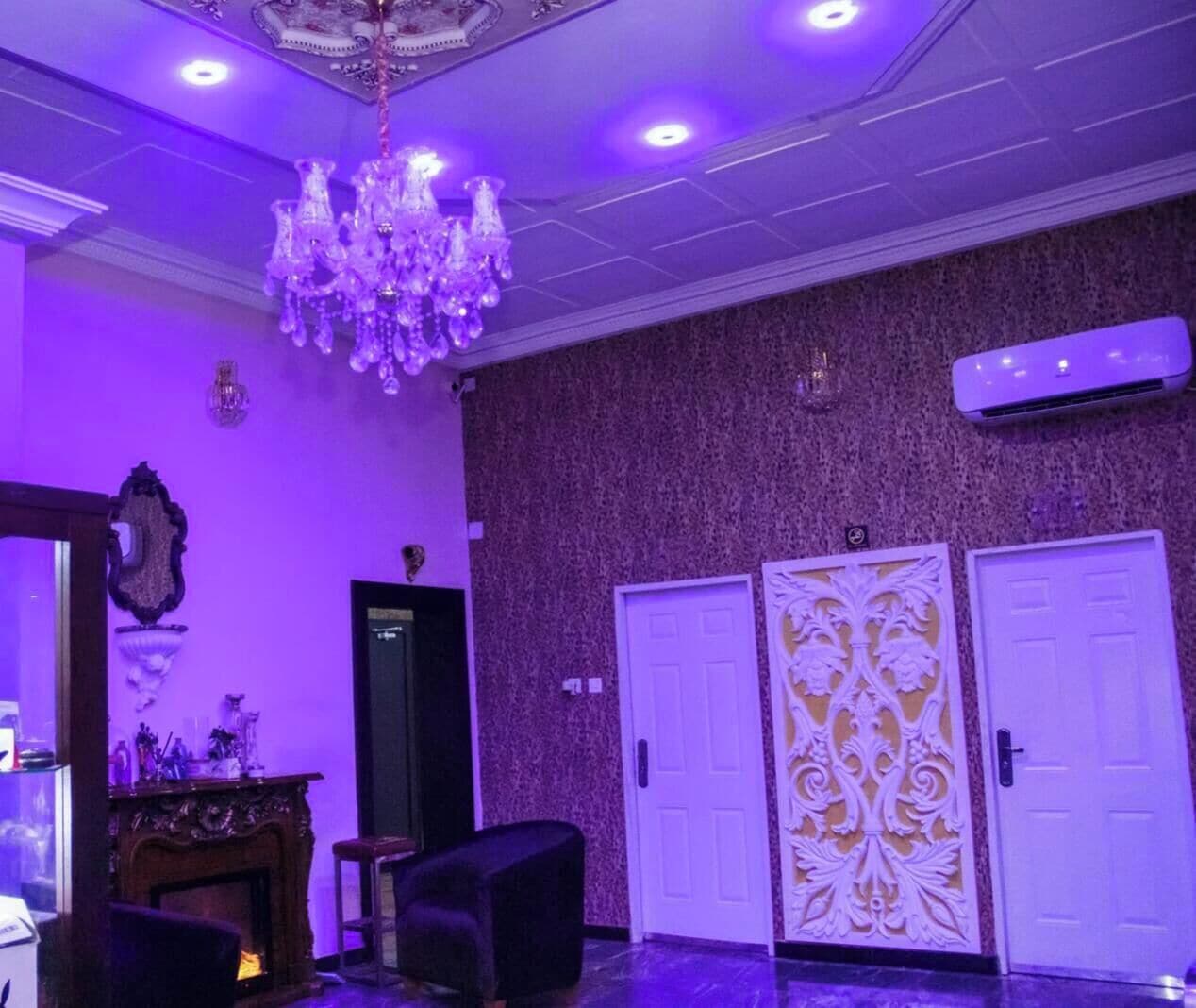 A room with a chandelier, two doors, a fireplace, and a wall-mounted air conditioner.
