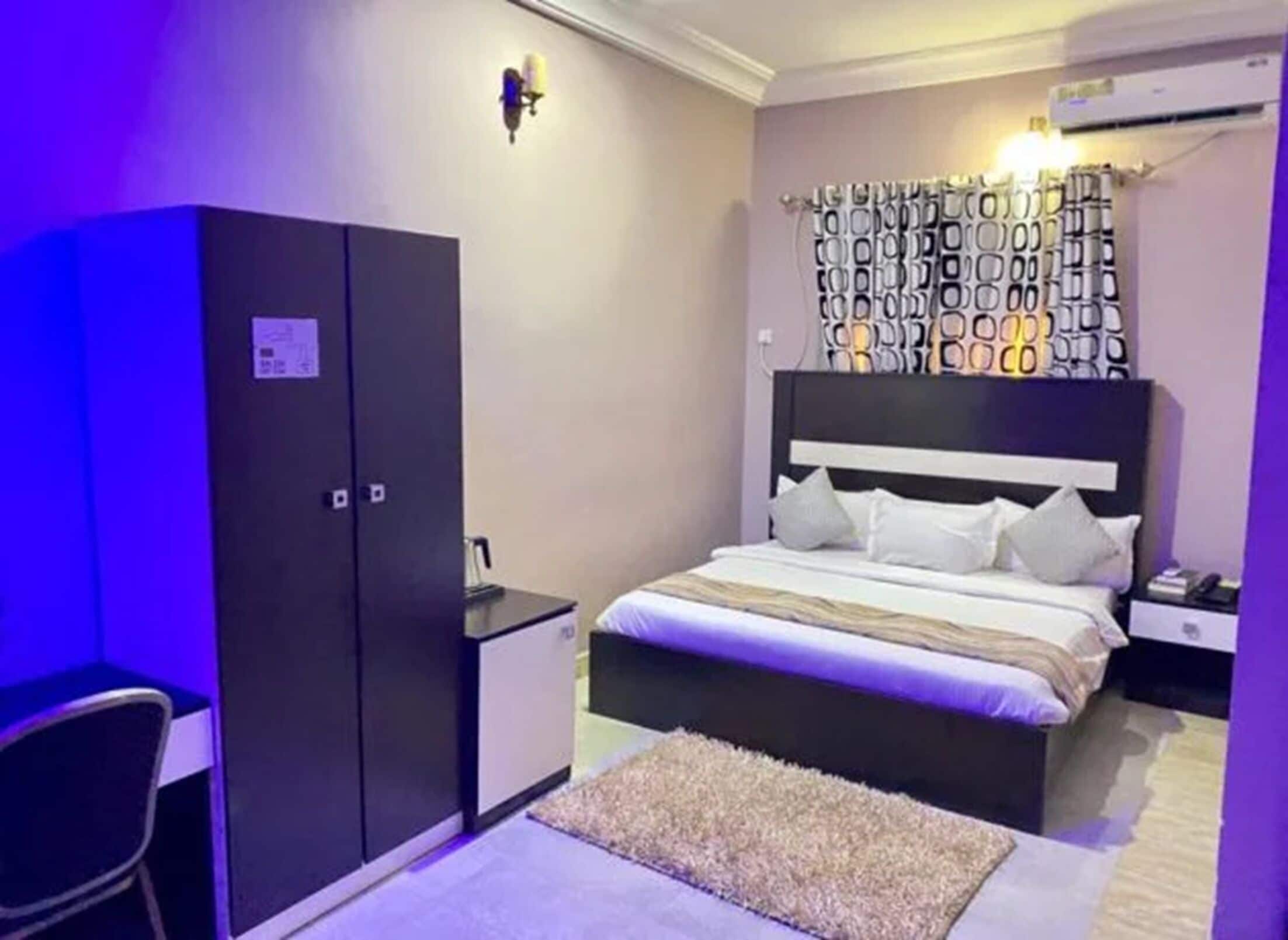 Un dormitorio con cama, armario, escritorio y cabecera estampada.