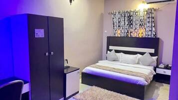 Un dormitorio con cama, armario, escritorio y cabecera estampada.