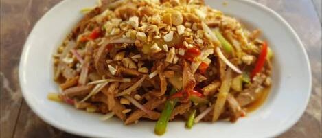 A plate of stir-fried noodles with vegetables and peanuts.