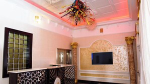 A lobby with a reception desk, a large TV screen, and a decorative chandelier. - Garden Atlantis Hotel (Enugu)