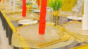 A long dining table with yellow tablecloths and gold accents, surrounded by chairs. - Garden Atlantis Hotel (Enugu)