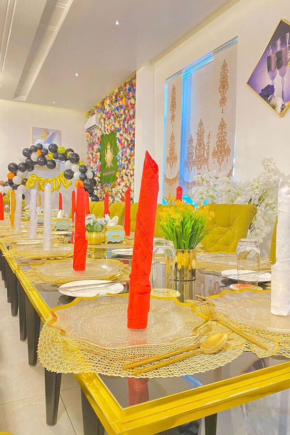 A long dining table with yellow tablecloths and gold accents, surrounded by chairs. - Garden Atlantis Hotel (Enugu)