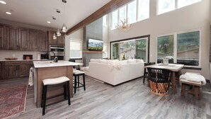 A spacious kitchen with wooden cabinets, a central island, and a dining area with a large window offering a mountain view.