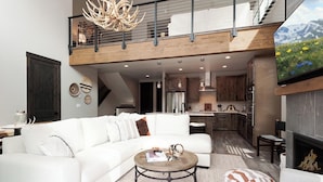 A modern living room with a white sectional sofa, a round wooden coffee table, and a fireplace.