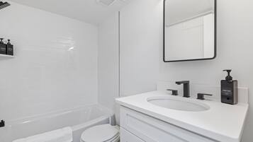 A modern bathroom with a white sink, mirror, and toilet.