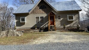 A wooden house with a gabled roof, a front porch, and a small front yard.