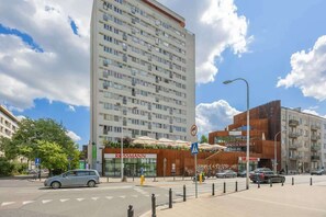 Un hotel moderno con un cartel llamativo de 'ROSSMANN', un paso de peatones y una calle con coches.