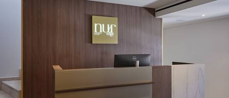 A reception desk with a sign reading "nur edge" and a Dell laptop.
