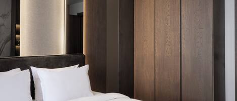 Una habitación de hotel moderna con una cama grande, paneles de madera oscura y una columna imponente.