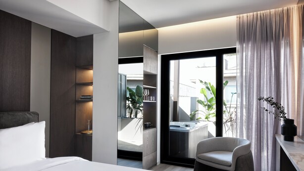 Een moderne hotelkamer met een groot bed, een zithoek, uitzicht op het omliggende landschap en een badkamer met bad.