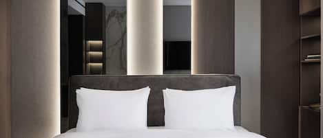 A modern hotel room with a large bed, dark wood paneling, and a large mirror.
