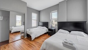Une chambre moderne avec deux lits, un miroir et une table de chevet.