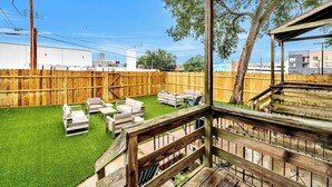 A backyard with a wooden deck, outdoor furniture, and a fenced area. - Entire building in The Grove, Perfect for Groups! (St. Louis)