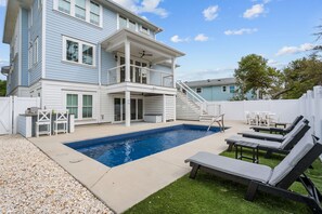 A two-story house with a swimming pool, outdoor seating, and a covered patio area.