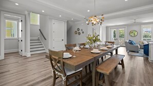 A spacious dining area with a wooden table set for four, surrounded by wooden chairs. - Seas the Day, gorgeous private home, heated pool (Kure Beach)