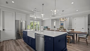 A modern kitchen with a central island, built-in appliances, and pendant lighting. - Seas the Day, gorgeous private home, heated pool (Kure Beach)