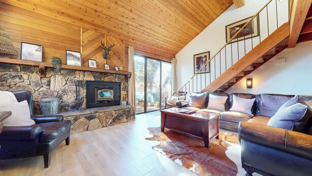A cozy living room with a stone fireplace, leather furniture, and a wooden staircase. - Large Townhouse, Washer/Dryer, Quiet Location. Pool & Tennis Courts On-site (Mammoth Lakes)