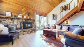 A cozy living room with a stone fireplace, leather furniture, and a wooden staircase. - Large Family Townhome, Private Washer/Dryer, Cozy Fireplace. On Shuttle Route (Mammoth Lakes)